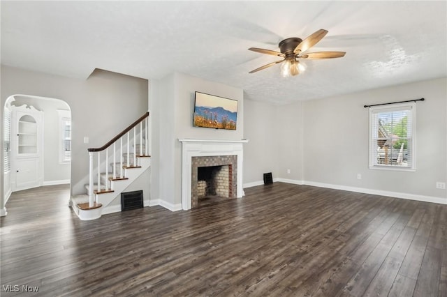 unfurnished living room featuring dark wood finished floors, a ceiling fan, stairs, a fireplace, and baseboards