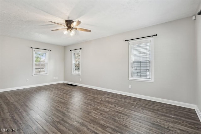 unfurnished room with ceiling fan, dark wood-style flooring, and baseboards