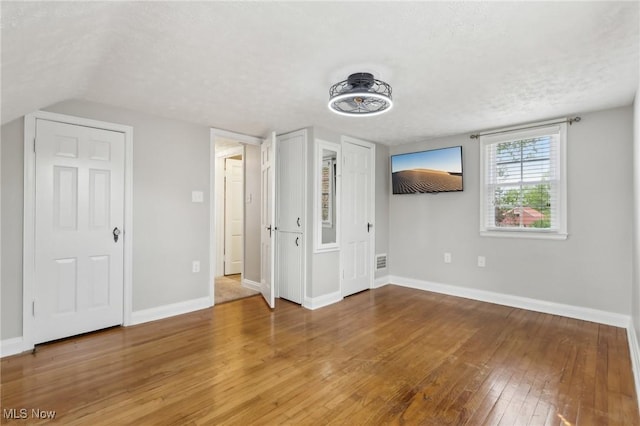 unfurnished bedroom with hardwood / wood-style floors, baseboards, and a textured ceiling