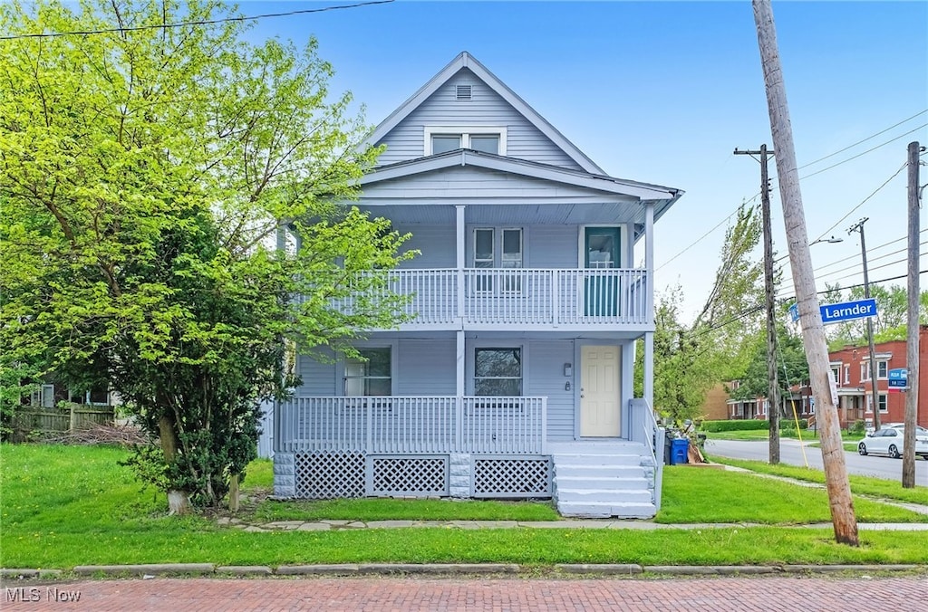 view of front facade with a porch, a balcony, and a front lawn