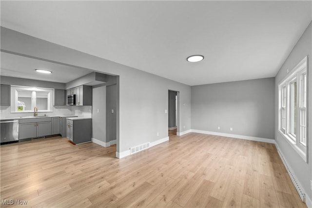 2394 Reimer Rd, Wadsworth, OH 44281 - unfurnished living room featuring a sink, light wood-style floors, baseboards, and healthy amount of natural light
