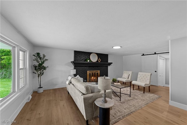 2394 Reimer Rd, Wadsworth, OH 44281 - living room with baseboards, light wood-style floors, a fireplace, a textured ceiling, and a barn door
