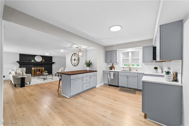 2394 Reimer Rd, Wadsworth, OH 44281 - kitchen featuring stainless steel dishwasher, gray cabinetry, open floor plan, a sink, and light wood-style floors