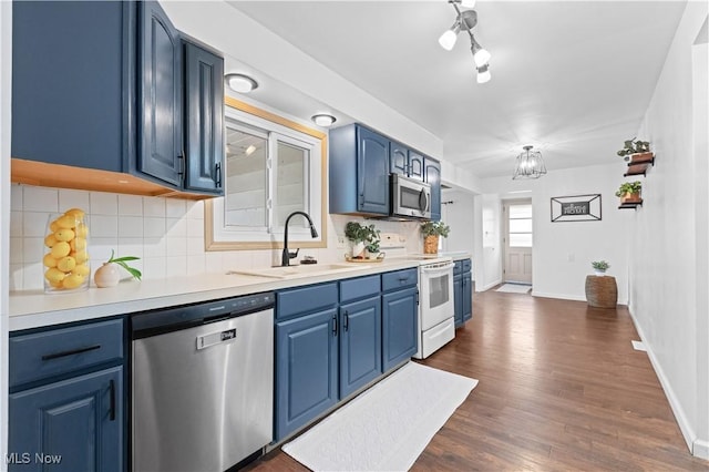 718 Starlight Dr, Seven Hills, OH 44131 - kitchen with appliances with stainless steel finishes, blue cabinets, backsplash, dark wood-style flooring, and a sink