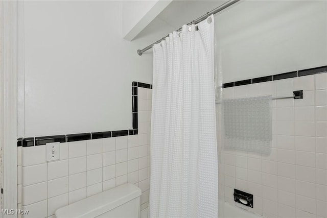 full bath featuring toilet, shower / tub combo with curtain, and tile walls