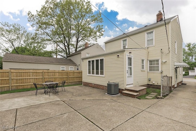 rear view of property featuring fence, a patio, cooling unit, a chimney, and outdoor dining space