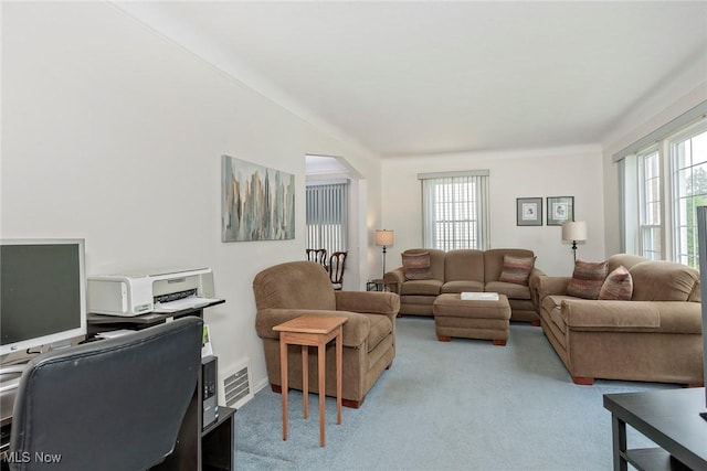 living area featuring light colored carpet and arched walkways