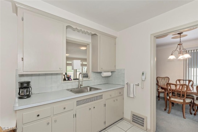 kitchen with light countertops, a sink, backsplash, and pendant lighting