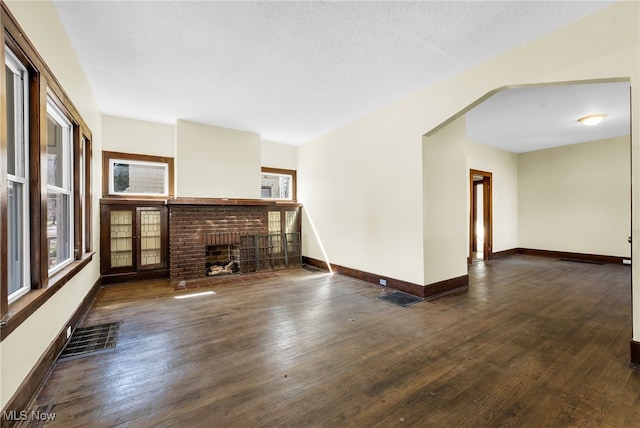 2142 W 95th St, Cleveland, OH 44102 - unfurnished living room featuring wood finished floors, baseboards, a brick fireplace, and plenty of natural light