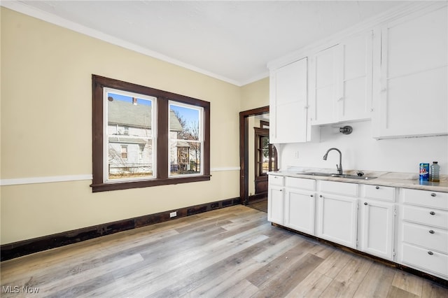 2142 W 95th St, Cleveland, OH 44102 - kitchen with a sink, light wood-type flooring, crown molding, white cabinetry, and baseboards