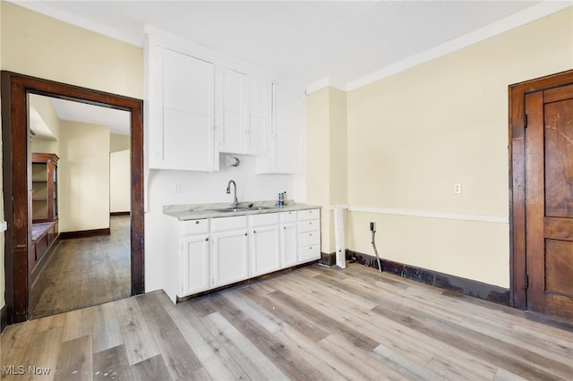 2142 W 95th St, Cleveland, OH 44102 - kitchen with light wood-type flooring, white cabinets, a sink, and baseboards