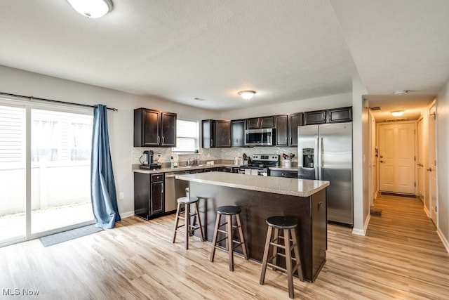 3585 Gerome Ct, Cleveland, OH 44105 - kitchen with stainless steel appliances, a breakfast bar area, light wood-style flooring, and tasteful backsplash