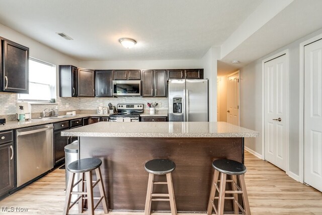 3585 Gerome Ct, Cleveland, OH 44105 - kitchen featuring stainless steel appliances, a breakfast bar area, light wood-type flooring, and a kitchen island