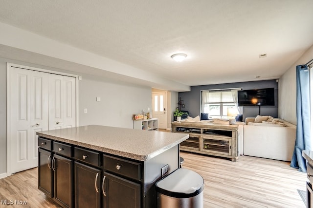 3585 Gerome Ct, Cleveland, OH 44105 - kitchen featuring light wood-type flooring, open floor plan, a kitchen island, light countertops, and dark brown cabinetry
