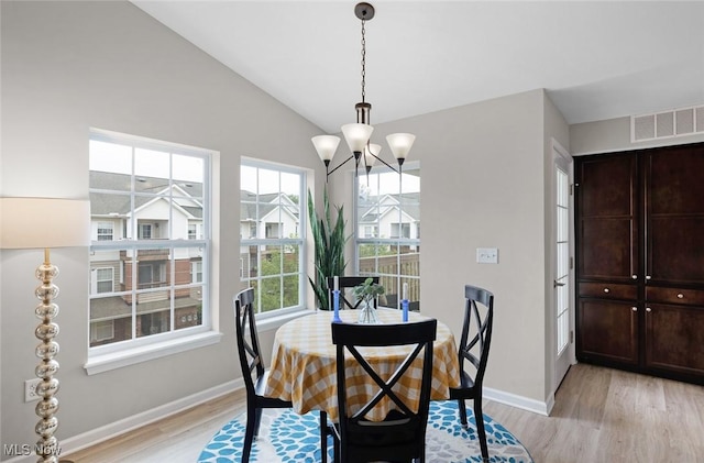dining room with light wood finished floors, baseboards, a chandelier, and lofted ceiling