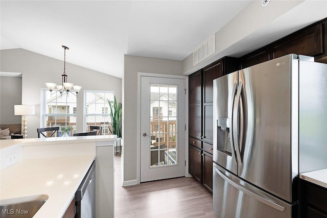 kitchen with appliances with stainless steel finishes, light wood finished floors, light countertops, a chandelier, and dark brown cabinets
