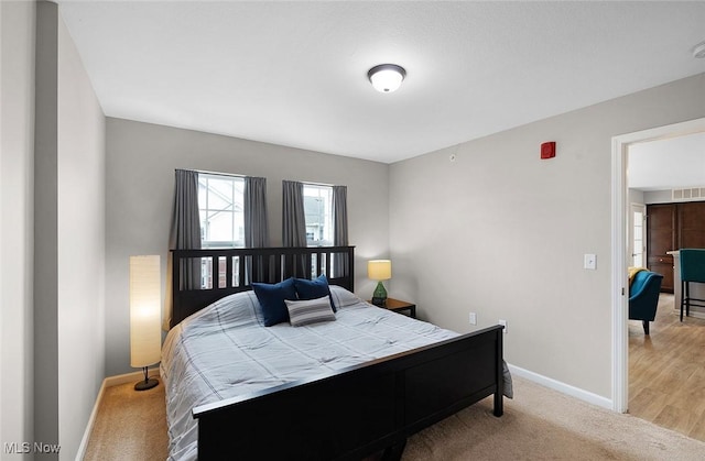 bedroom with light colored carpet and baseboards