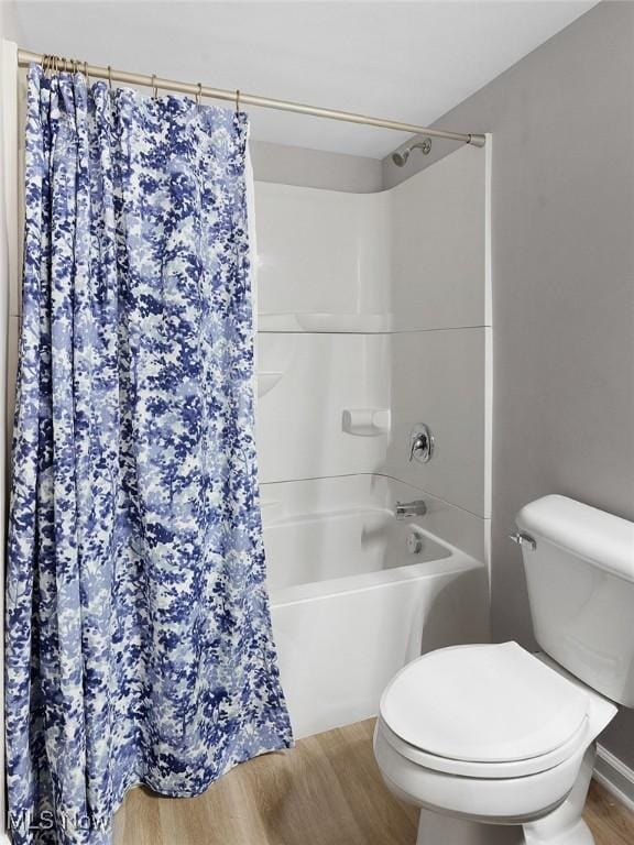 full bathroom with wood finished floors, toilet, and shower / bathtub combination with curtain
