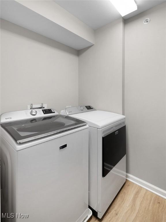 laundry area with washer and clothes dryer, light wood-type flooring, and baseboards