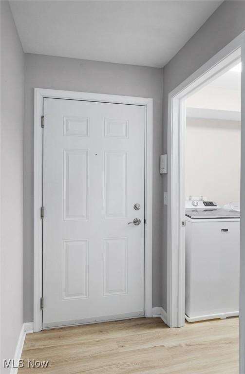 entryway with washer / clothes dryer, light wood-style floors, and baseboards