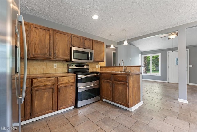 548 51st St SW, Canton, OH 44706 - kitchen featuring appliances with stainless steel finishes, a peninsula, a sink, a textured ceiling, and tasteful backsplash
