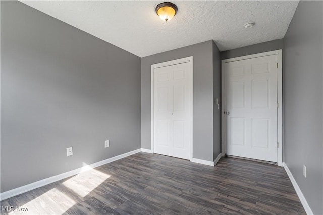 548 51st St SW, Canton, OH 44706 - unfurnished bedroom with dark wood-style floors, baseboards, a closet, and a textured ceiling