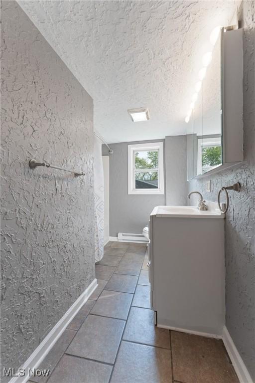 548 51st St SW, Canton, OH 44706 - full bathroom featuring vanity, healthy amount of natural light, a textured ceiling, baseboard heating, and tile patterned floors