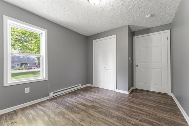 548 51st St SW, Canton, OH 44706 - unfurnished bedroom featuring a baseboard heating unit, wood finished floors, baseboards, and a textured ceiling