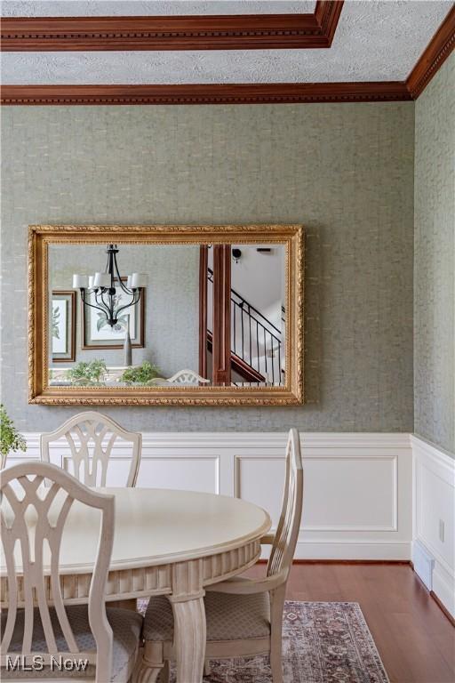 425 Woodside Ave, Jefferson, OH 44047 - dining area featuring crown molding, wood finished floors, wainscoting, wallpapered walls, and a chandelier
