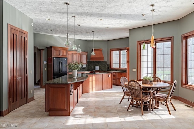 425 Woodside Ave, Jefferson, OH 44047 - kitchen featuring freestanding refrigerator, a center island, tasteful backsplash, brown cabinets, and a textured ceiling