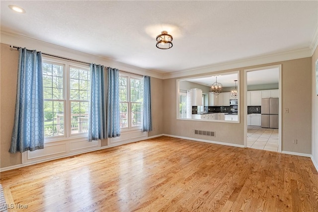 3020 Irena Ln, Twinsburg, OH 44087 - unfurnished living room featuring ornamental molding, a chandelier, light wood-style floors, and baseboards