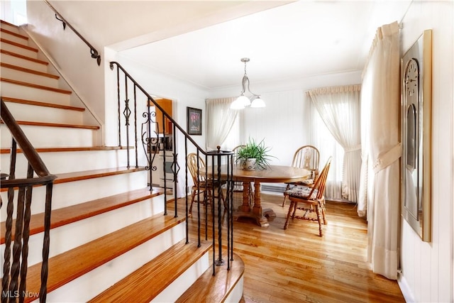 dining room featuring wood finished floors, a chandelier, stairway, and crown molding