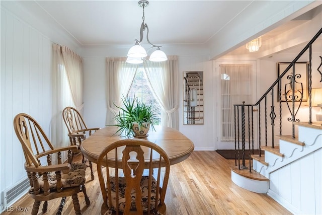 dining room featuring wood finished floors, stairway, and a chandelier
