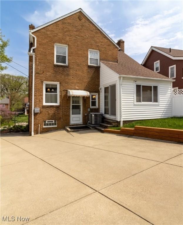back of property with a chimney, brick siding, fence, and a patio area