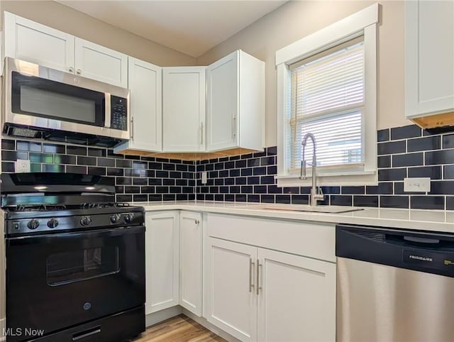 kitchen featuring appliances with stainless steel finishes, a sink, and white cabinetry