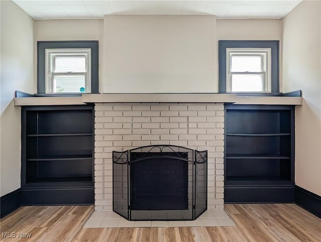detailed view of wood finished floors and a brick fireplace