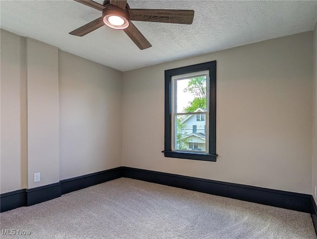 spare room featuring carpet floors, a ceiling fan, a textured ceiling, and baseboards