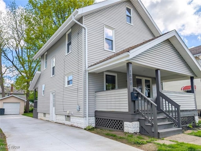 traditional style home with covered porch, an outdoor structure, concrete driveway, and a detached garage