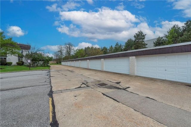 view of asphalt road with community garages