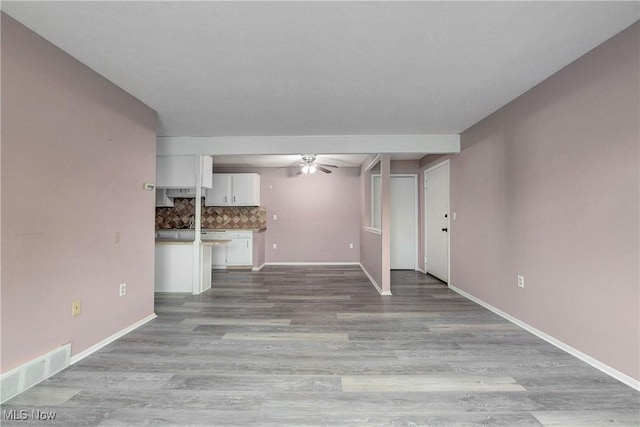 unfurnished living room featuring ceiling fan, wood finished floors, and baseboards