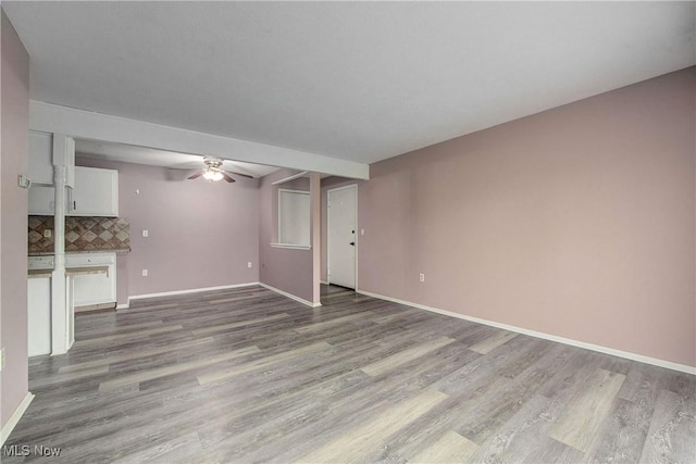 unfurnished living room with wood finished floors, ceiling fan, and baseboards