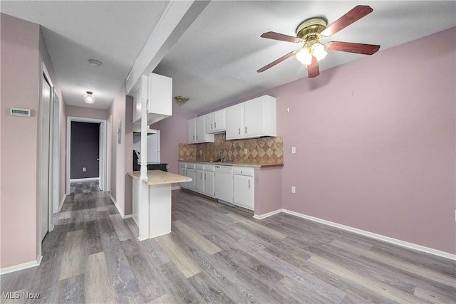 kitchen with a ceiling fan, backsplash, white cabinetry, wood finished floors, and light countertops