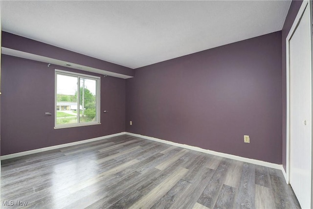 empty room featuring wood finished floors and baseboards