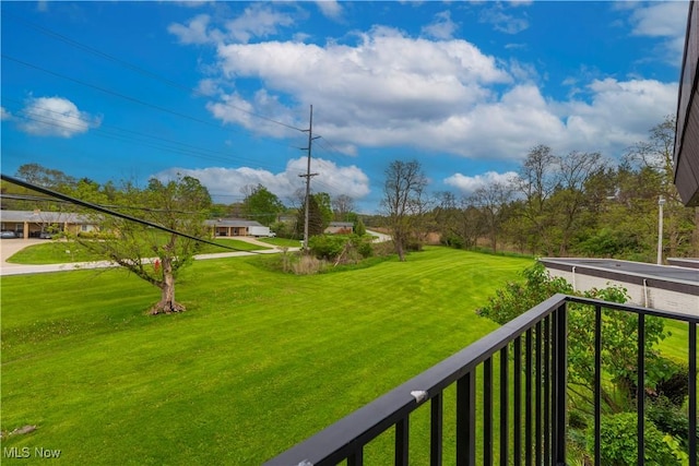 view of grassy yard with a balcony