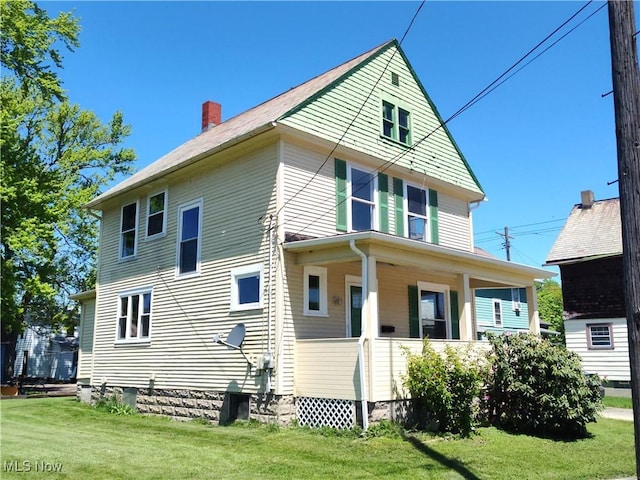 view of front of house featuring a front lawn, covered porch, and a chimney