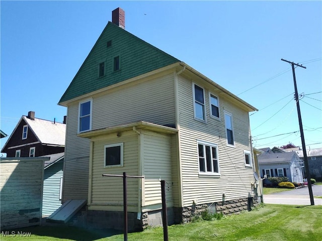 back of property with a chimney and a yard