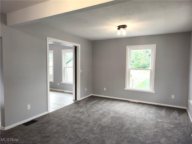 unfurnished room with carpet flooring, baseboards, and a textured ceiling