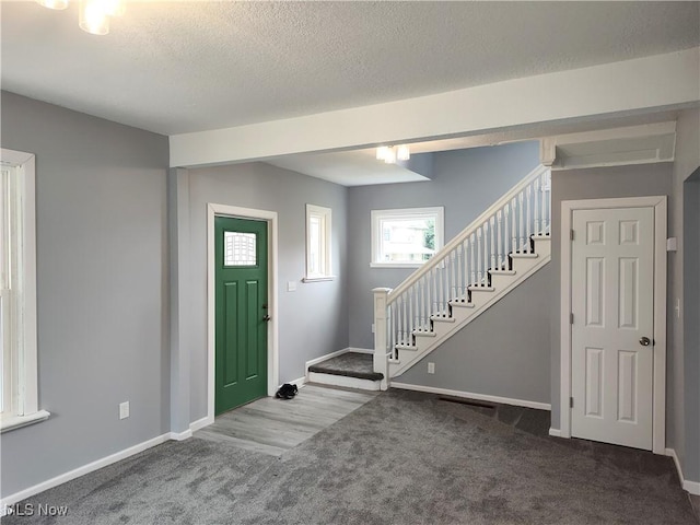 entrance foyer with stairway, carpet, baseboards, and a textured ceiling