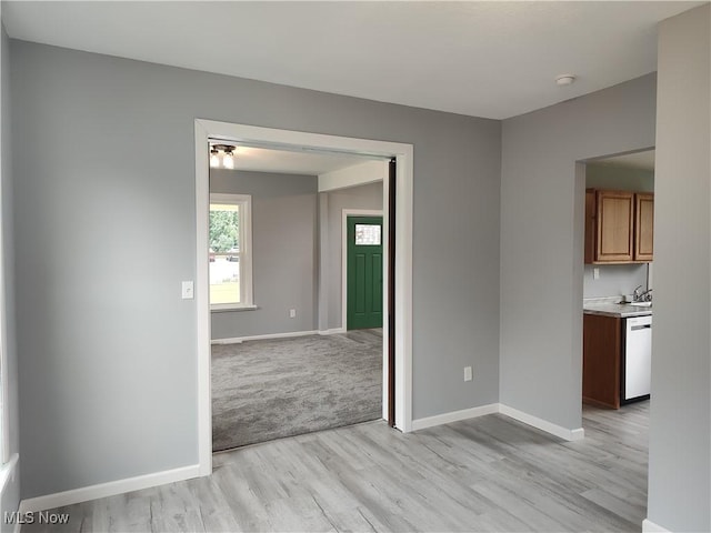 empty room with light wood-style flooring, baseboards, and a smoke detector