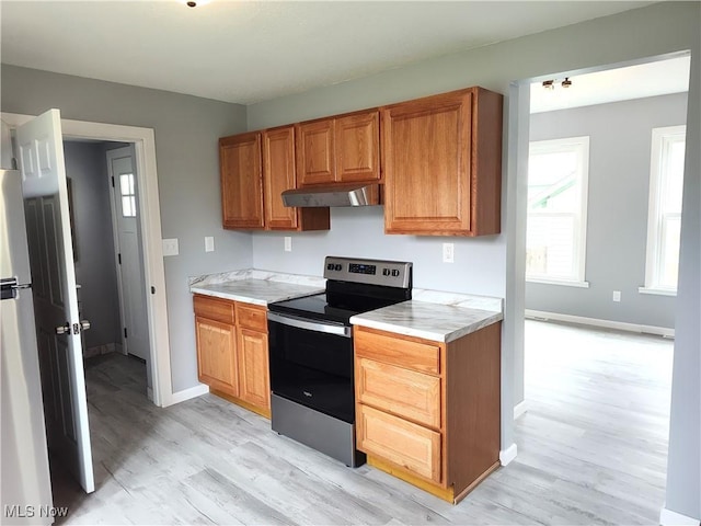 kitchen with stainless steel appliances, light wood-style floors, light countertops, baseboards, and brown cabinetry